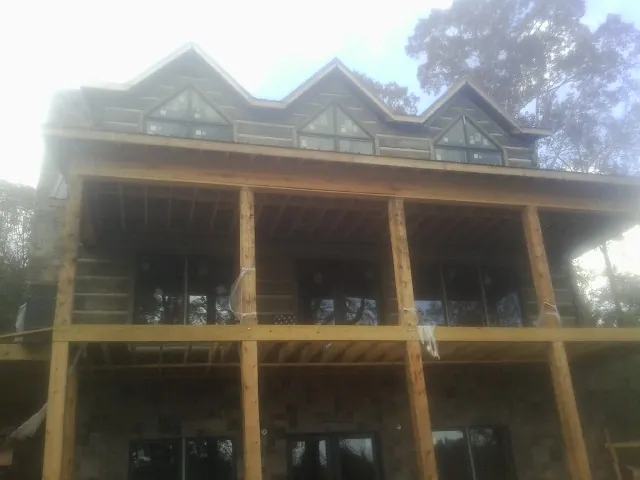 Dormers and porch framing on a large log home under construction — Roof Coating work by our crew in Tipton